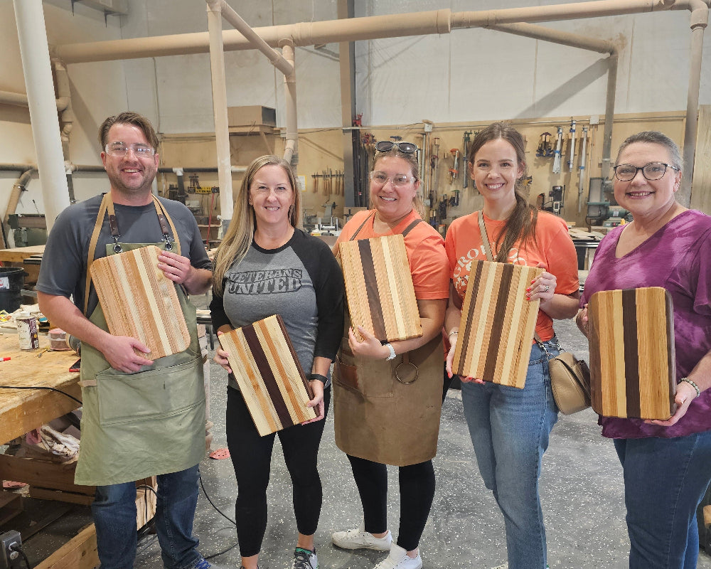 Group of people holding wooden boxes in a workshop setting